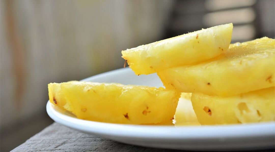 Färska skivor av ananas på en vit tallrik.