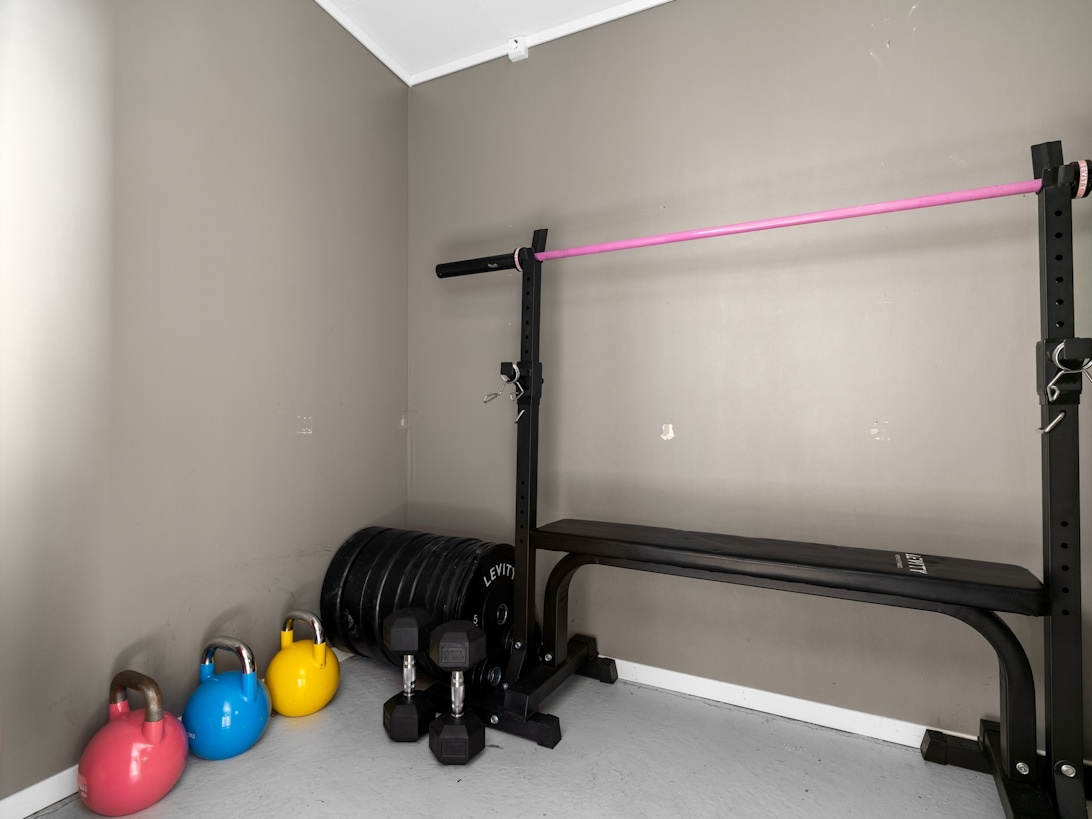 En kompakt träningshörna med färgglada kettlebells, hantlar och gummiband.